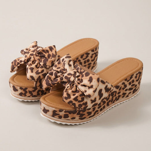 Leila leopard bow wedge slides, pair at a three-quarter angle