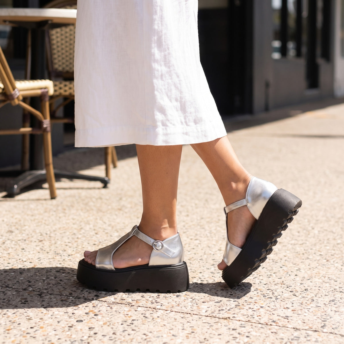 Marlee silver T-strap platform sandals worn walking on a café footpath