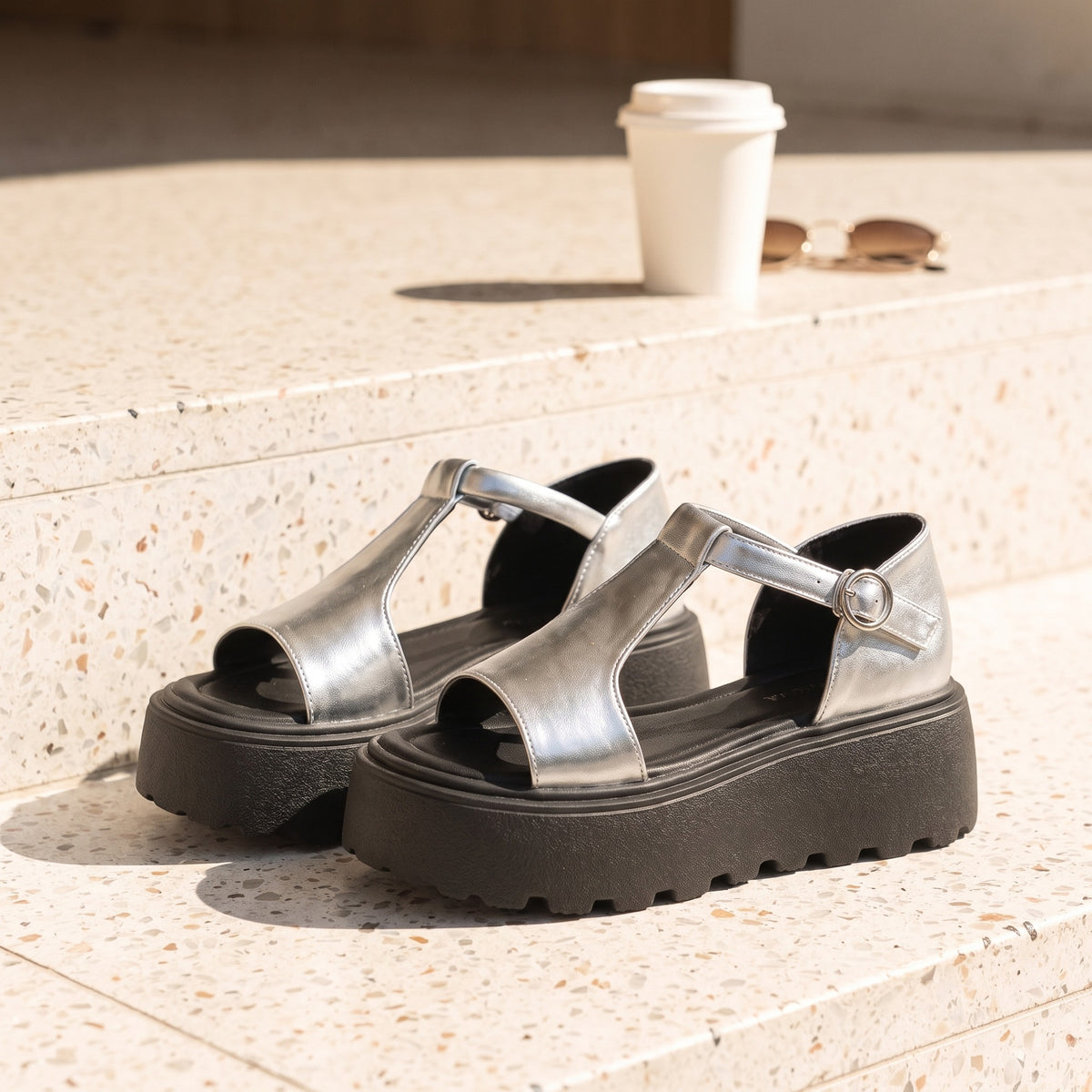 Marlee silver T-strap platform sandals on a terrazzo café step